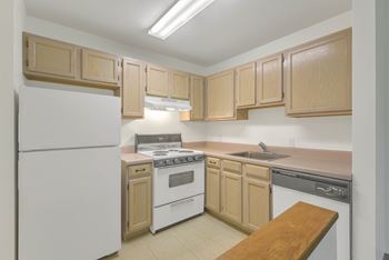 Apartment kitchen with wood cabinets and white appliances